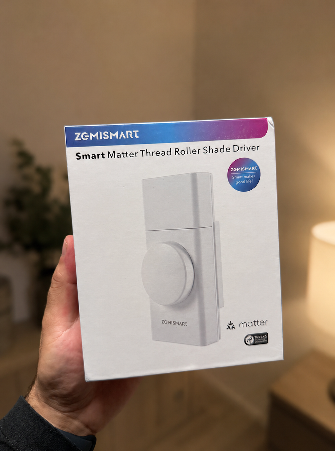 Point of view image of a hand holding the Zemismart Roller Shade Driver box.